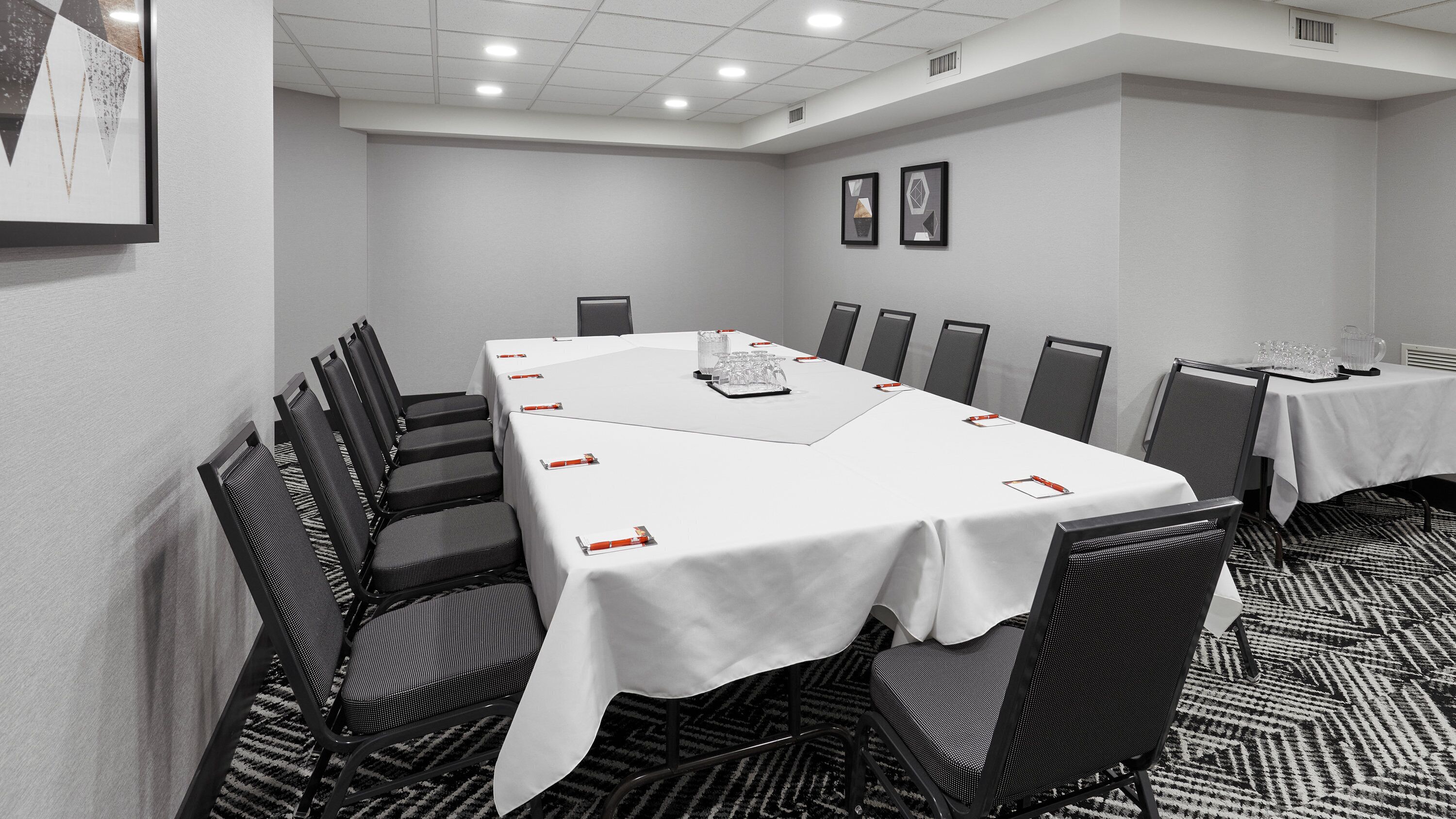 Una sala conferenze con un lungo tavolo, sedie e pavimento rivestito di moquette.