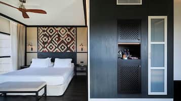 Une chambre d’hôtel moderne équipée d’un lit, de tables de chevet, d’un bureau, d’une armoire et d’un ventilateur de plafond.