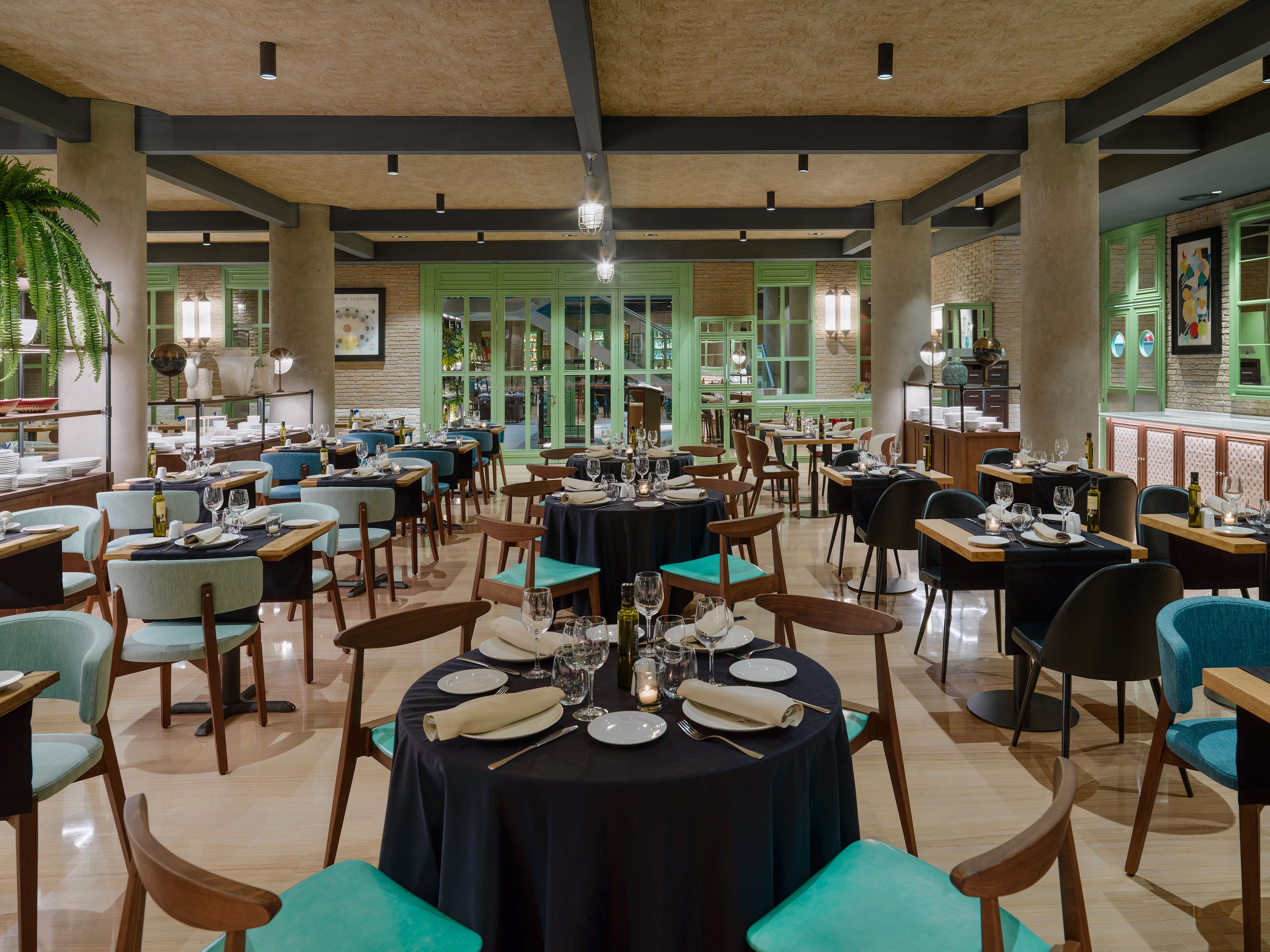 Um restaurante com várias mesas, cadeiras e armários verdes.