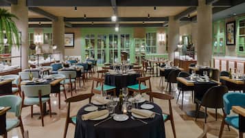 Um restaurante com várias mesas, cadeiras e armários verdes.