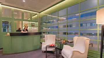 A lobby with a reception desk, seating area, and large windows.