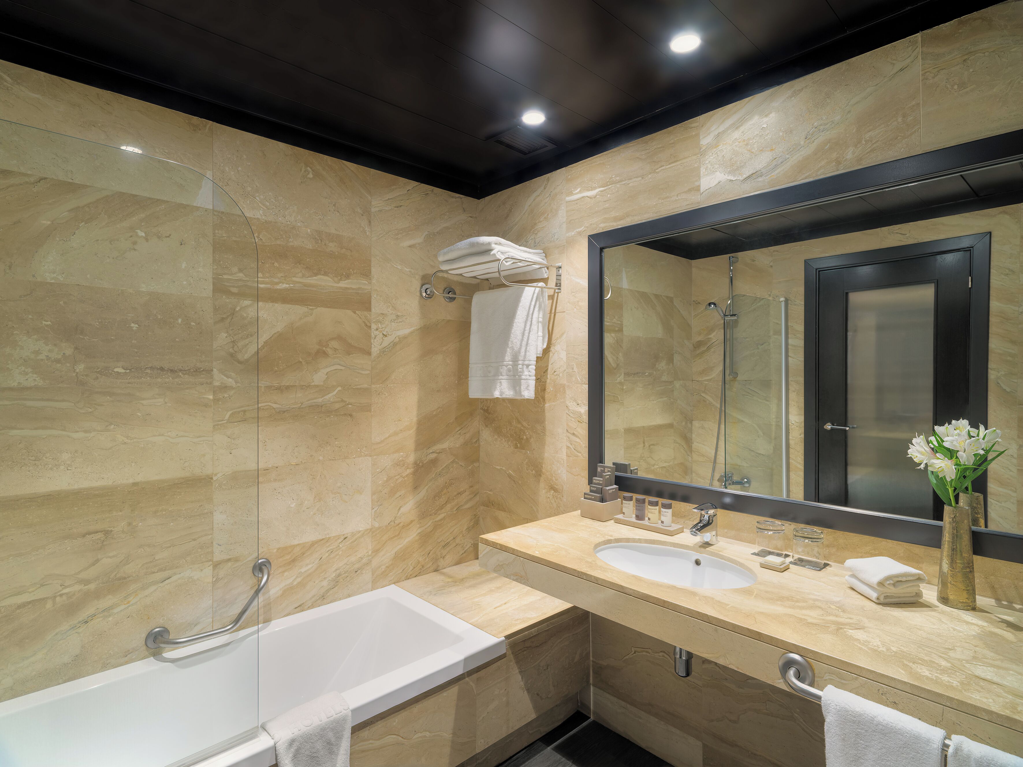 Un bagno moderno con una vasca, un lavandino, uno specchio grande e una doccia.