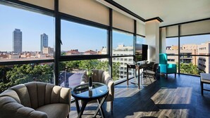 A modern apartment with large windows, a flat-screen TV, a dining area, and a sofa. - H10 Marina Barcelona (Barcelona)
