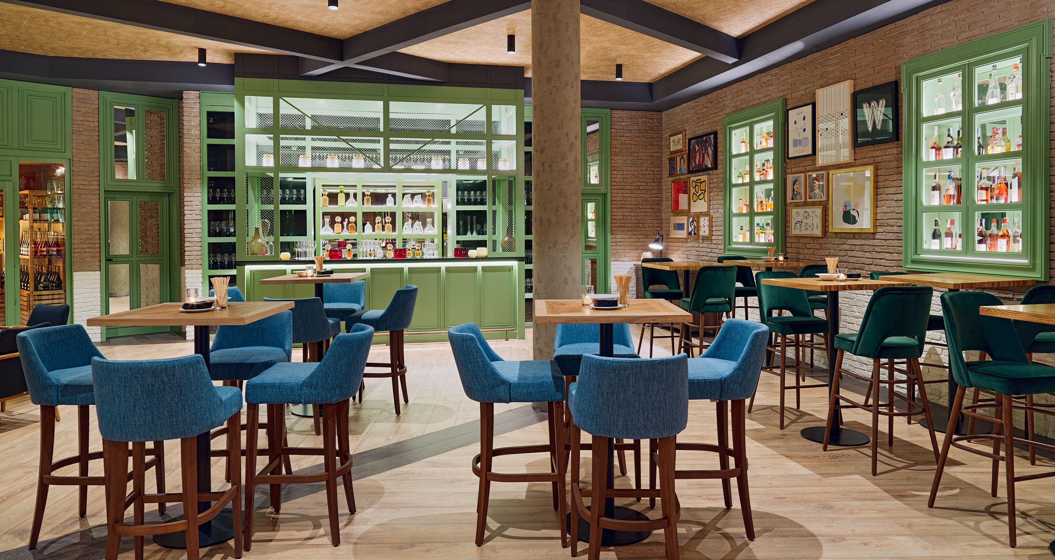 Un restaurante con áreas de bar enmarcadas en verde, sillas tapizadas en azul y mesas de madera.