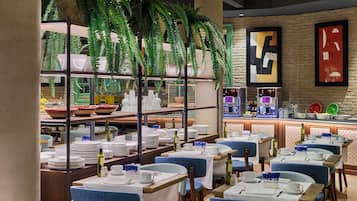Un restaurant avec des tables dressées pour le service, un bar à café et des plantes décoratives.