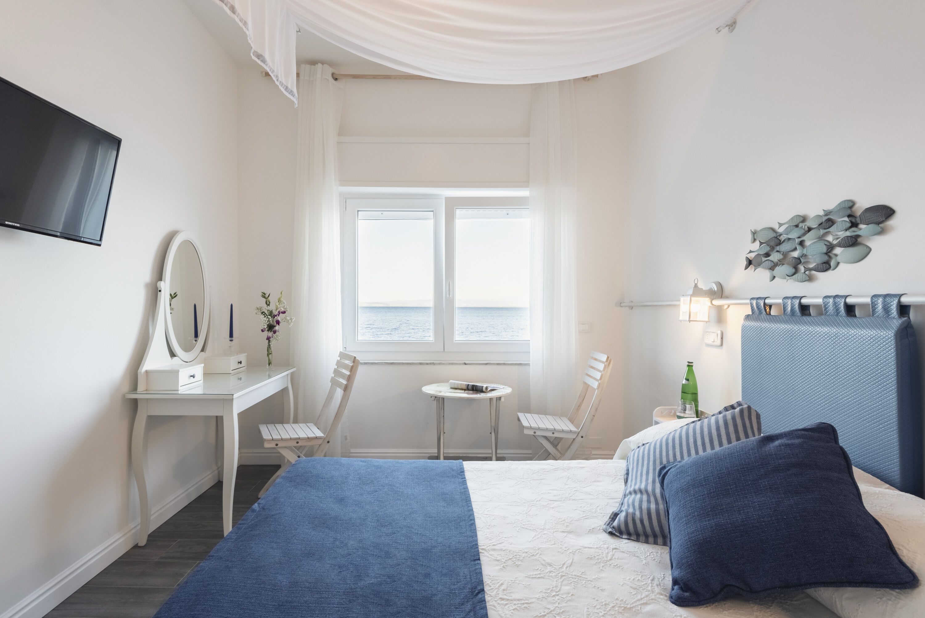 Une chambre à coucher comprenant un lit, un bureau, une chaise, une petite table et un téléviseur fixé au mur.