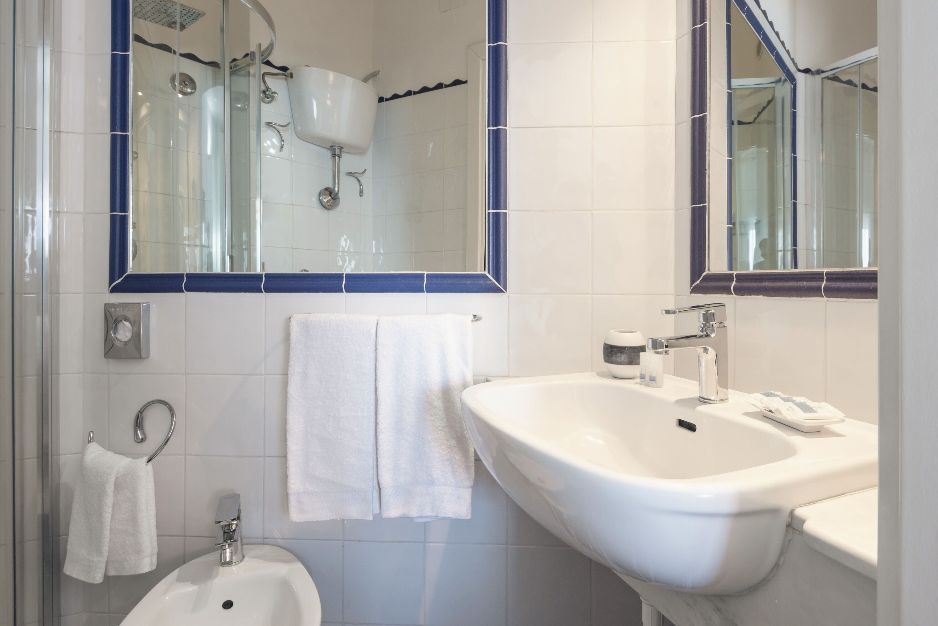 A bathroom with a white sink, a mirror, a shower, and a towel rack.