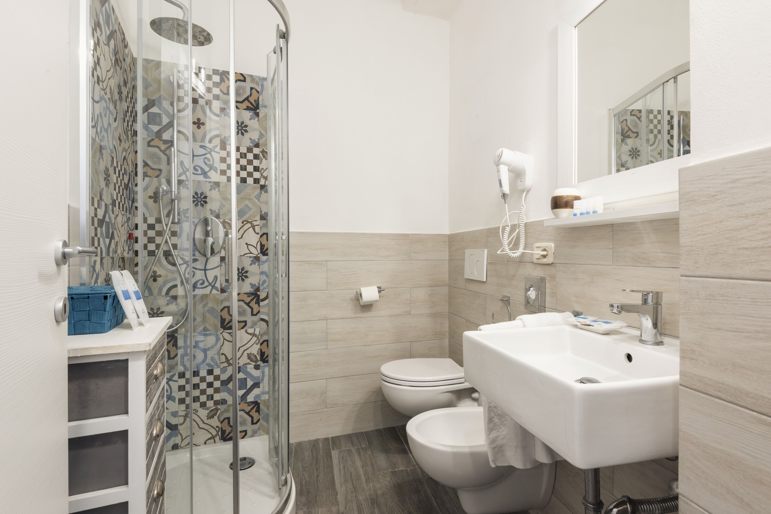 Un baño con ducha, inodoro, lavabo y espejo.