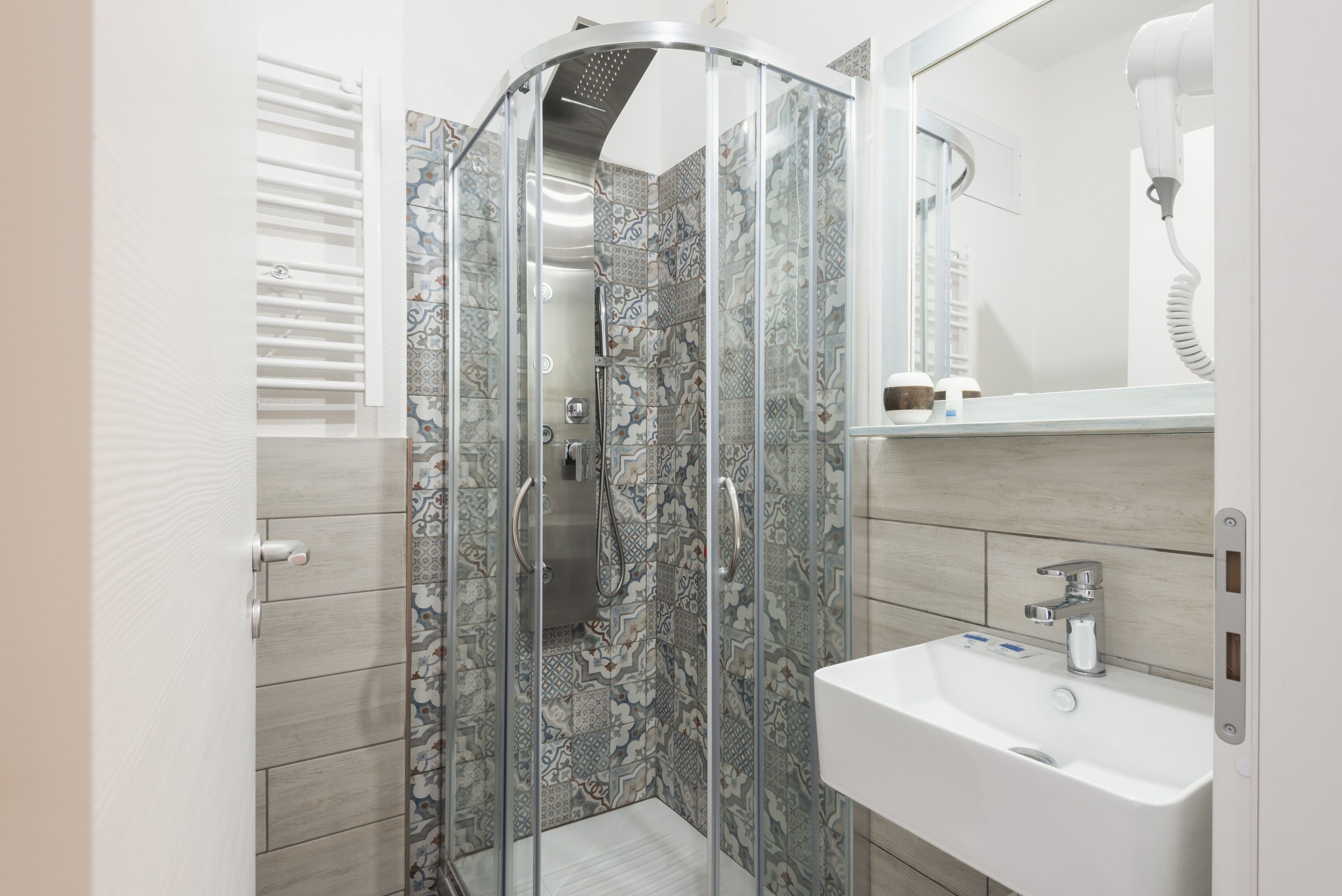Une salle de bain moderne avec une douche à parois de verre, un lavabo blanc et un miroir.