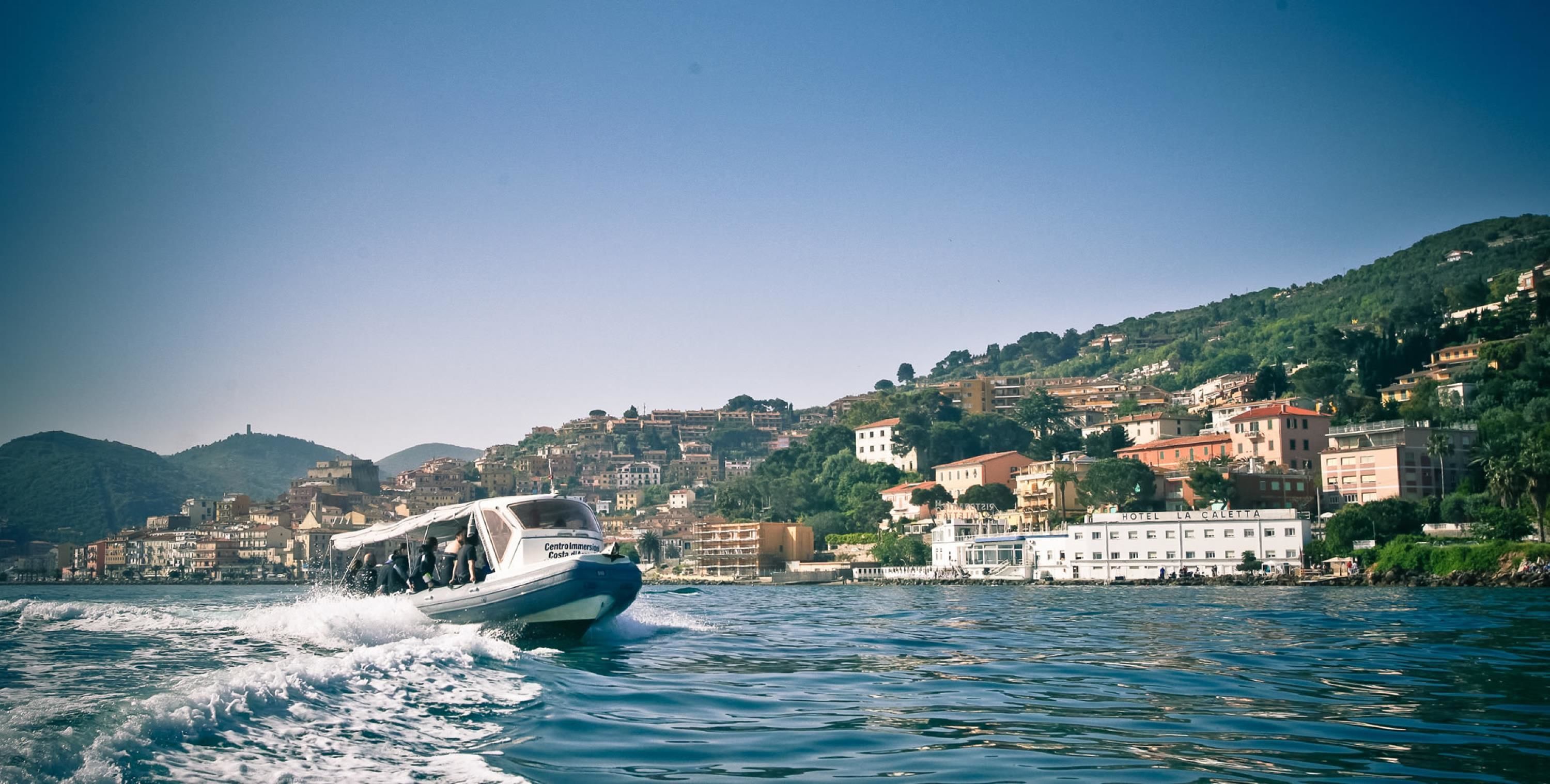 A boat moving on water with a coastal town in the background.