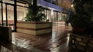 Un patio empapado de baldosas con macetas y un edificio de dos pisos con puertas de cristal.