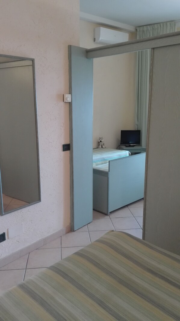 A hotel room with a bed, a desk with a computer, a television, and a window with curtains.