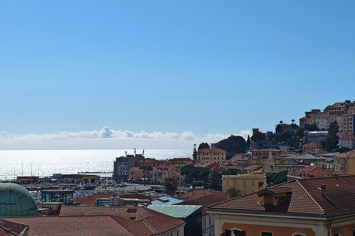 Un paisaje urbano costero con edificios, un puerto deportivo y cielo despejado.