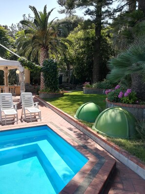 A swimming pool with white lounge chairs, surrounded by lush greenery and a well-maintained lawn. - Residence Hotel Miramare (Imperia)