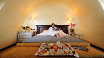 A person reading in a room with a breakfast tray on the bed.