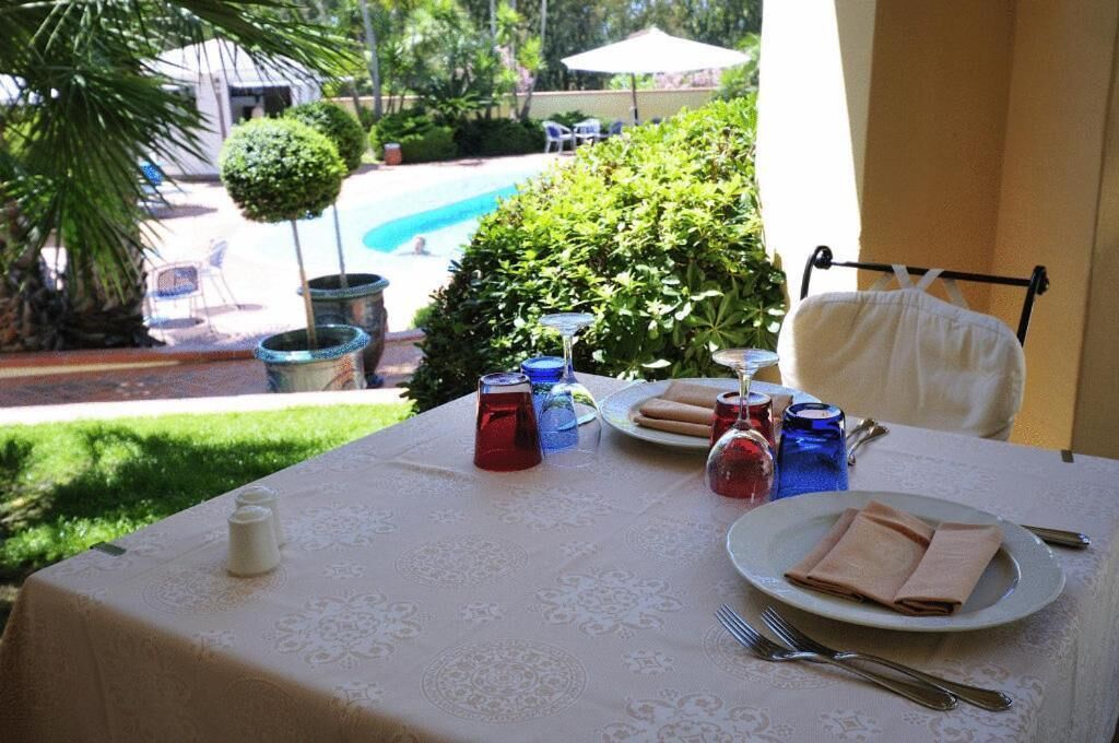 Un tavolo imbandito per due con vista su una piscina e vegetazione.