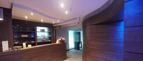 A reception area with a wooden reception desk, a glass display case, and a wall-mounted information board.