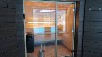 A modern interior with a sliding glass door leading to a wooden interior, a metal bucket with a broom, and a trash bin.