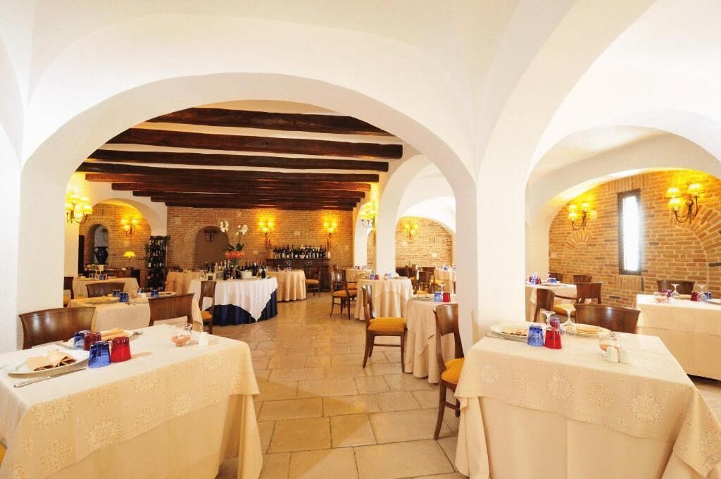 A restaurant with multiple tables, brick walls, and exposed wooden beams.