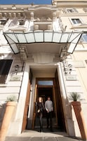 The entrance of a hotel with a classic facade, a covered entrance, and a sign indicating the hotel name.