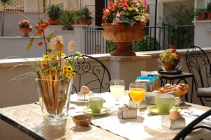 Una tavola per la colazione con un vaso di fiori, una ciotola di frutta e diversi prodotti per la colazione.