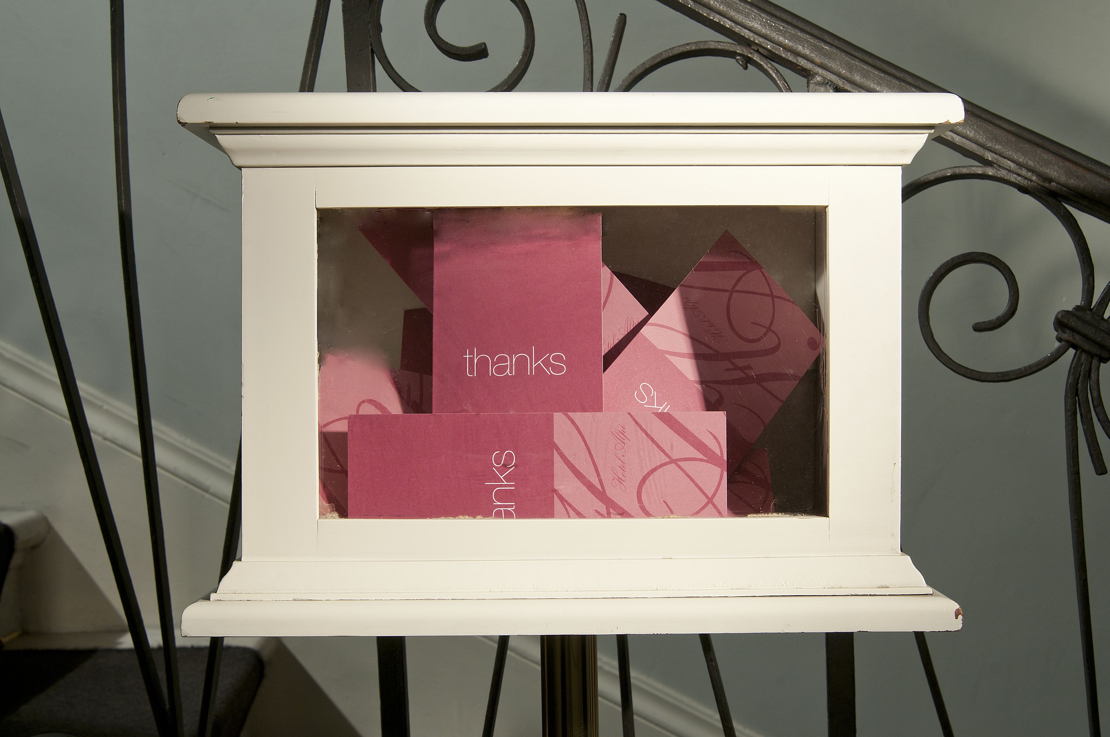 A white display case with a glass front containing several pink cards with the word "thanks" visible.