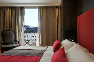 Una camera d'albergo con un letto, una sedia, un tavolino e vista sulla città dalla finestra.