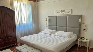 A bedroom with a bed, bench, nightstand, lamp, and wardrobe.