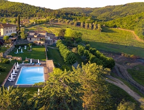 A resort with a swimming pool, lounge chairs, and a view of the surrounding countryside. - Hotel Casafrassi Wine Resort (Castellina in Chianti)