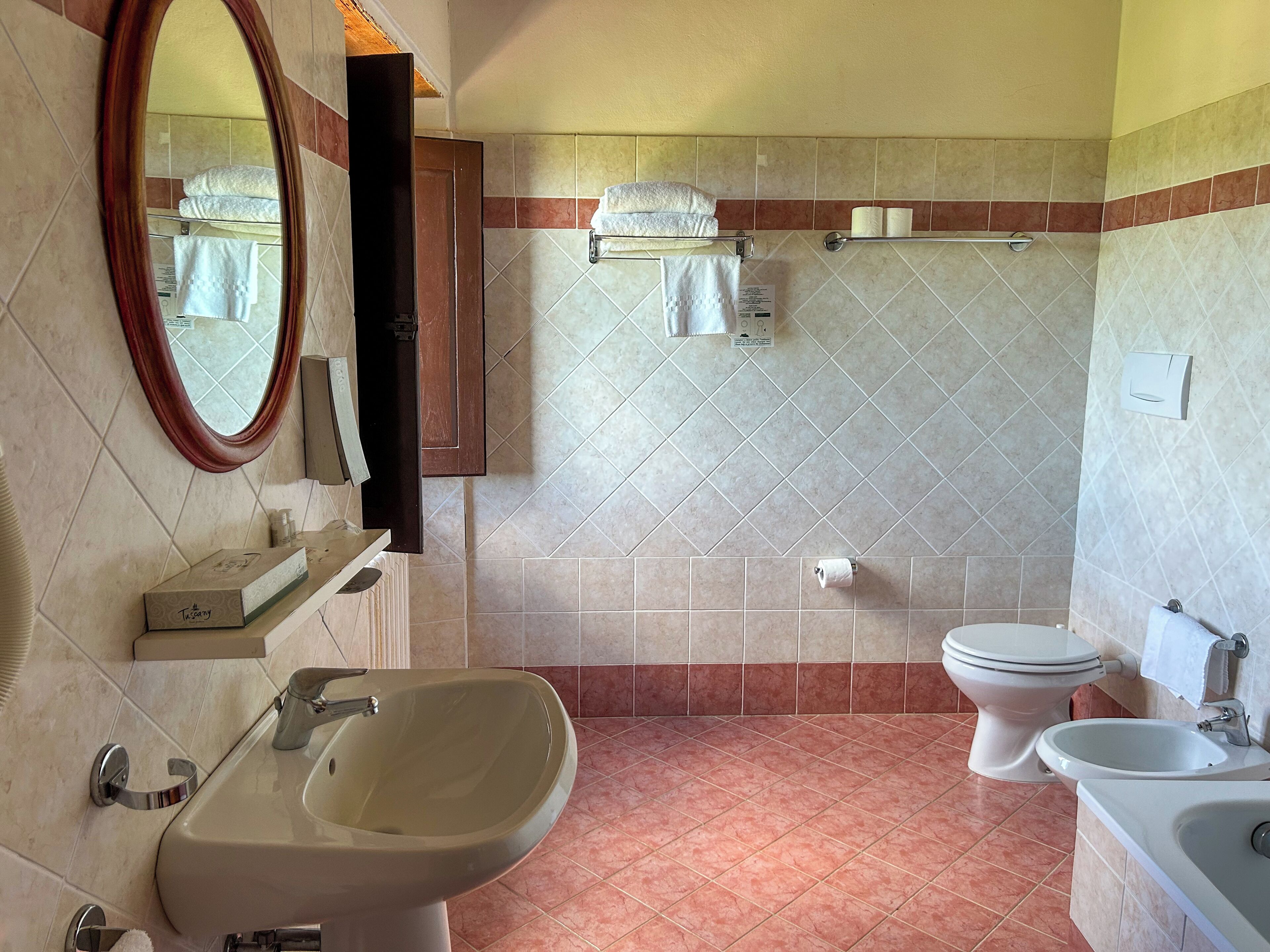 A bathroom with a sink, bidet, toilet, and towel rack.