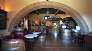 A bar area with brick arches, wooden barrels, leather seating, and a wine rack.