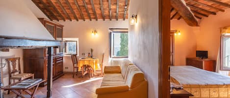 A cozy room with a wooden ceiling, a sofa, a bed, and a small table.