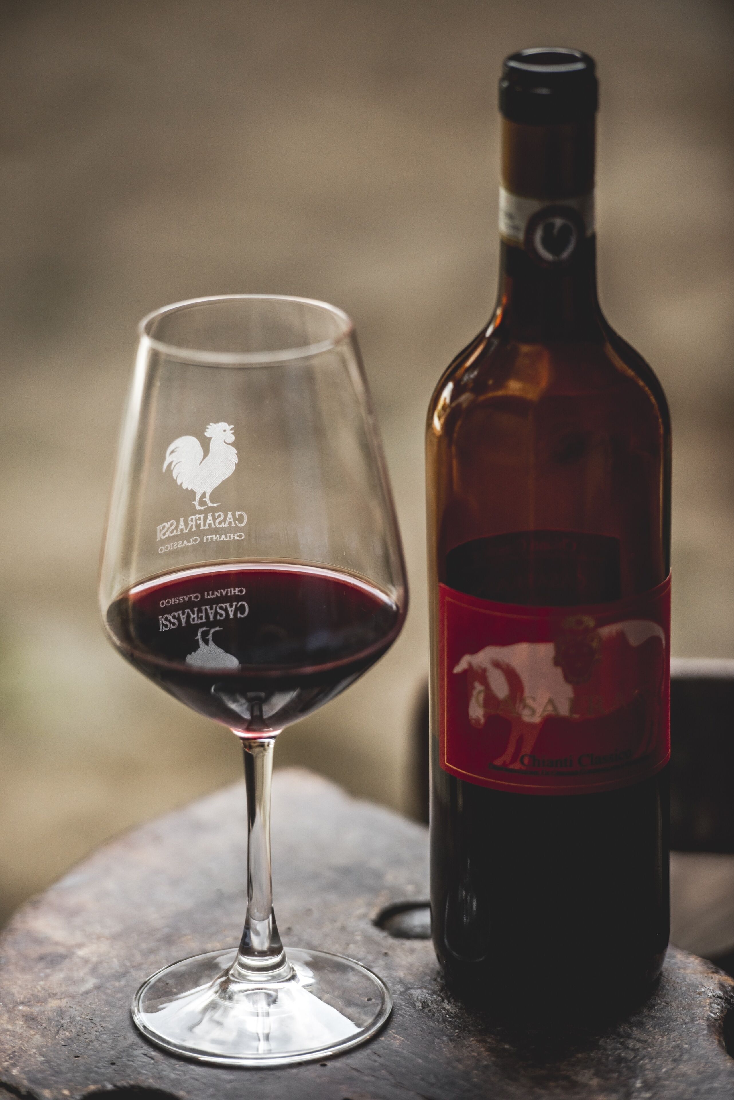 Un verre à vin et une bouteille ornés d’un logo représentant un coq et de l’inscription « CASARATTI CLASSICO ».
