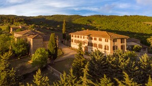 A traditional villa with a tiled roof, surrounded by lush greenery and hills.