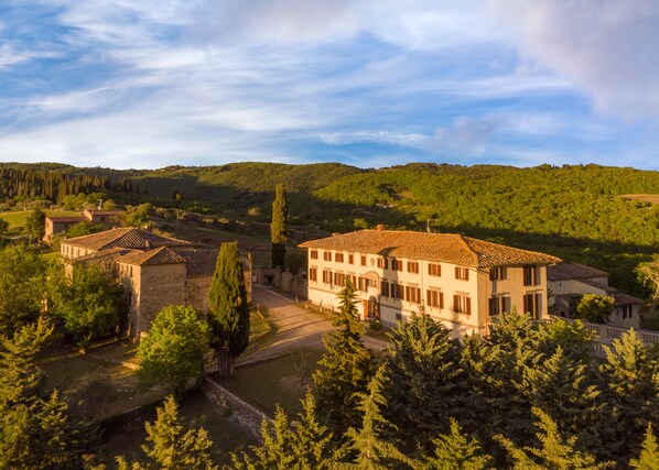 A traditional villa with a tiled roof, surrounded by lush greenery and hills. - Hotel Casafrassi  (Castellina in Chianti)