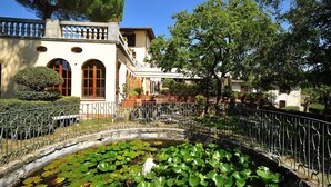 A building with arched windows, a courtyard with a pond, and a metal fence.