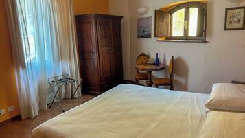 Ein Schlafzimmer mit Bett, einem Kleiderschrank, einem Tisch mit Stühlen, einem Fenster und einer Wandlampe.