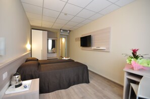 A hotel room with two beds, a TV mounted on the wall, a small table with a kettle, and a decorative plant. - Best Quality Hotel Politecnico (Turin)