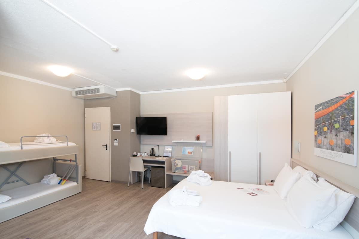 A hotel room with bunk beds, a desk, a TV, and a wardrobe.