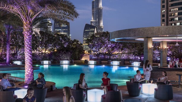 Un espace piscine aménagé sur le toit, avec des chaises longues et une vue sur le Burj Khalifa.