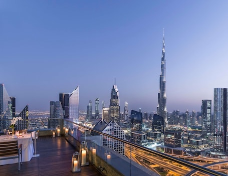A rooftop terrace with a cityscape view, featuring modern buildings and a prominent skyscraper.