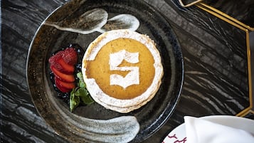 En desserttallrik med pannkakor och bär på ett marmorbord.