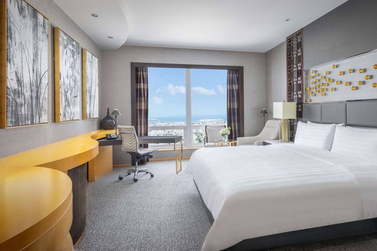 A hotel room with a large bed, a desk, and a view of the city.
