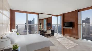 Une chambre d’hôtel moderne dotée d’un grand lit, d’un bureau et d’une télévision. La chambre dispose de grandes fenêtres offrant une vue sur la ville.
