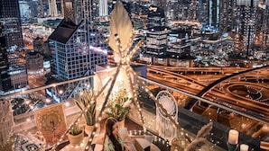 A rooftop terrace with a cityscape view, including a prominent skyscraper. The terrace is furnished with a sofa, chairs, and a dining table with fruit and candles. - Shangri-La Dubai (Dubai)
