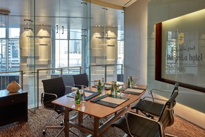 A conference room with a glass wall, a wooden table, and modern chairs.