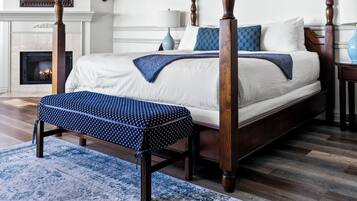 A four-poster bed with a wooden frame, a blue patterned bench, and a blue and white rug.