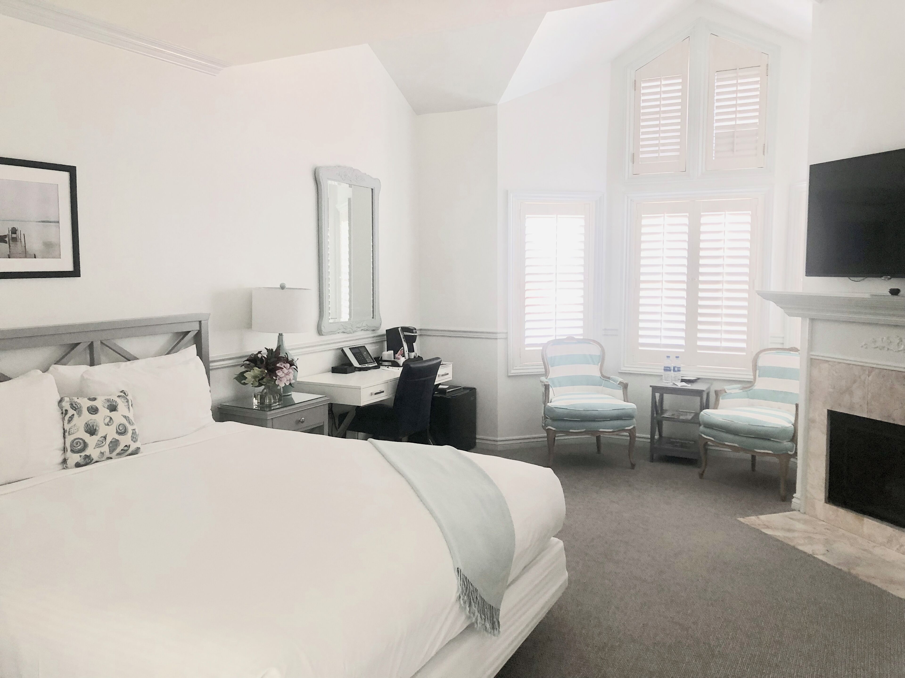 Une chambre d’hôtel avec un grand lit, un bureau avec un ordinateur, une chaise, une cheminée et un téléviseur.