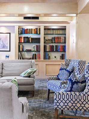 A living room with a sofa, armchair, and a bookshelf filled with books.