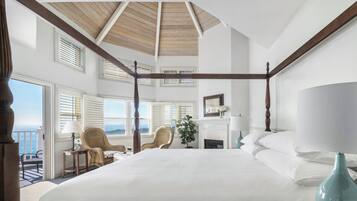 A spacious bedroom with a large bed, a wooden ceiling, and a balcony with a view.